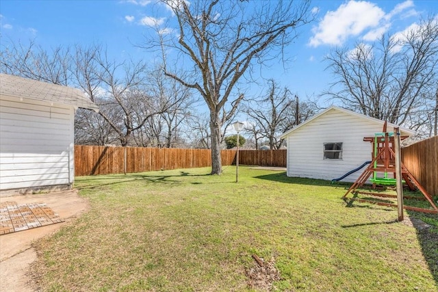 view of yard with an outbuilding, a fenced backyard, and a playground