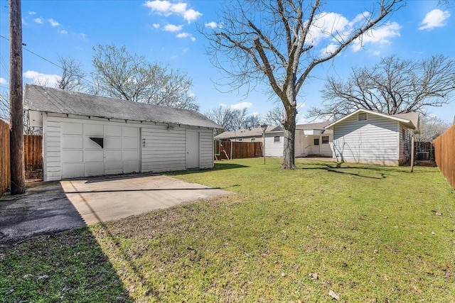 view of yard featuring an outbuilding, a detached garage, a fenced backyard, and driveway