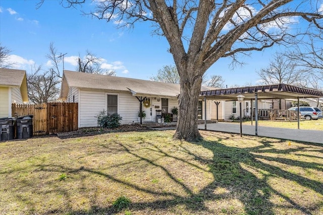 single story home with a front lawn, fence, a carport, and aphalt driveway