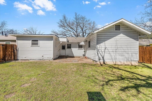 rear view of house featuring fence, a yard, and a patio