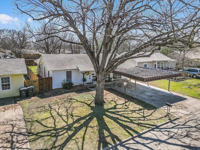 view of front of property featuring concrete driveway, fence, and roof with shingles