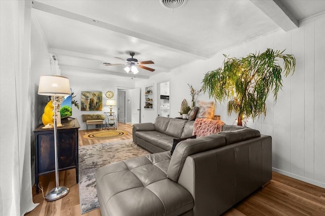 living area featuring a ceiling fan, beamed ceiling, wood finished floors, and visible vents