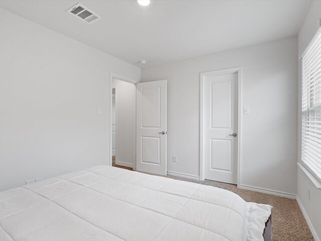 carpeted bedroom featuring visible vents and baseboards