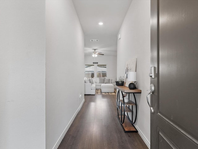 hallway with visible vents, baseboards, and dark wood finished floors