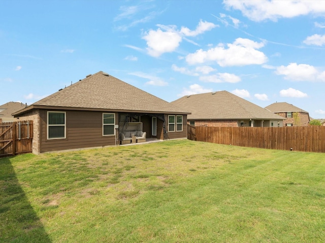 back of property with a yard, a patio area, a shingled roof, and a fenced backyard