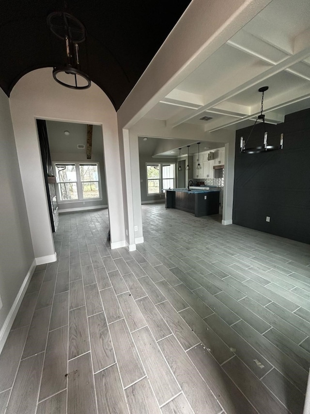 interior space with beamed ceiling, visible vents, baseboards, and wood finish floors