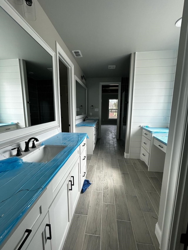 bathroom featuring a sink, visible vents, two vanities, and wood tiled floor