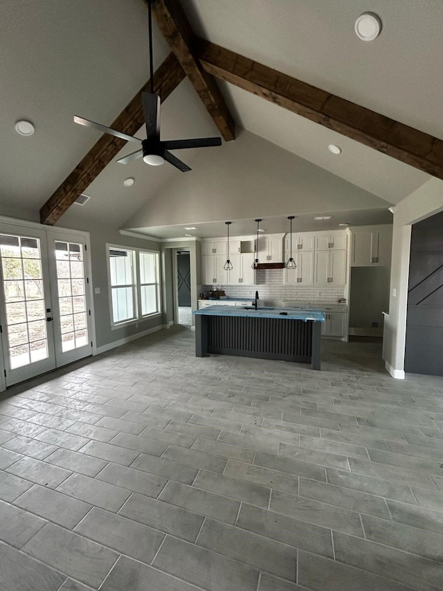 kitchen with backsplash, open floor plan, white cabinets, and beam ceiling