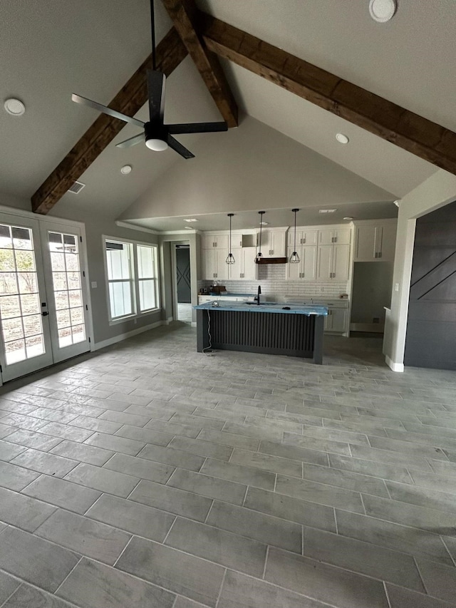 kitchen with open floor plan, white cabinets, beamed ceiling, and decorative backsplash