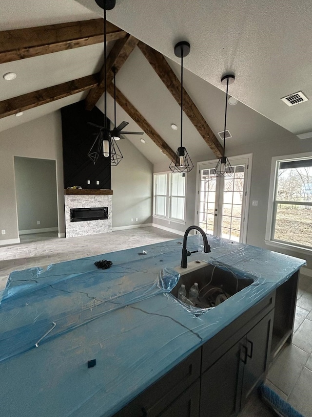 kitchen featuring lofted ceiling with beams, a healthy amount of sunlight, open floor plan, and a sink