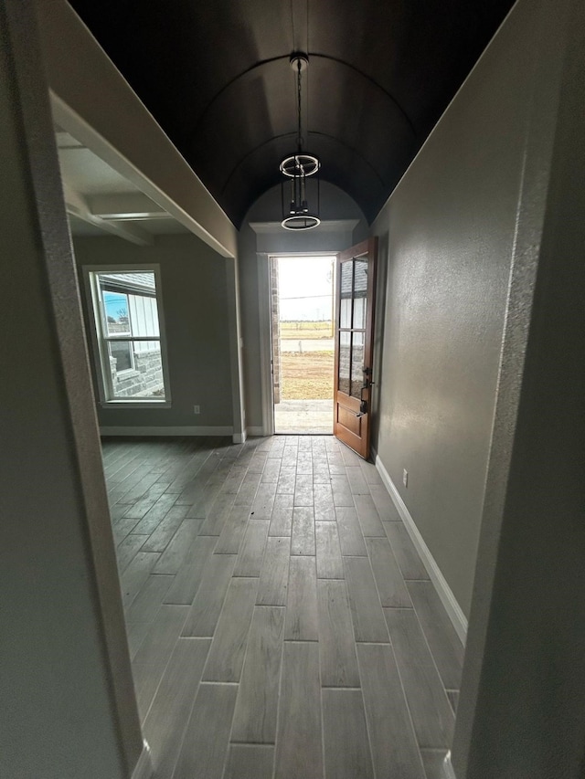 hall featuring vaulted ceiling, wood finished floors, and baseboards