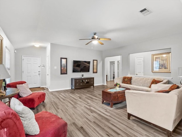 living room with a ceiling fan, wood finished floors, visible vents, baseboards, and vaulted ceiling