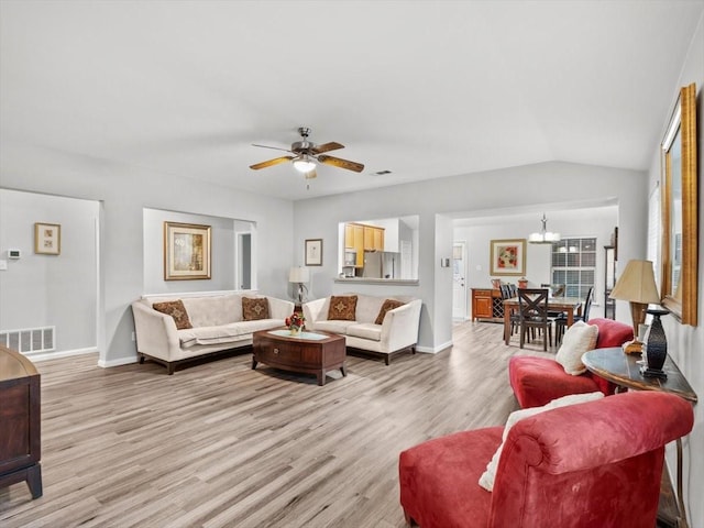 living area featuring visible vents, light wood-style flooring, ceiling fan with notable chandelier, baseboards, and vaulted ceiling