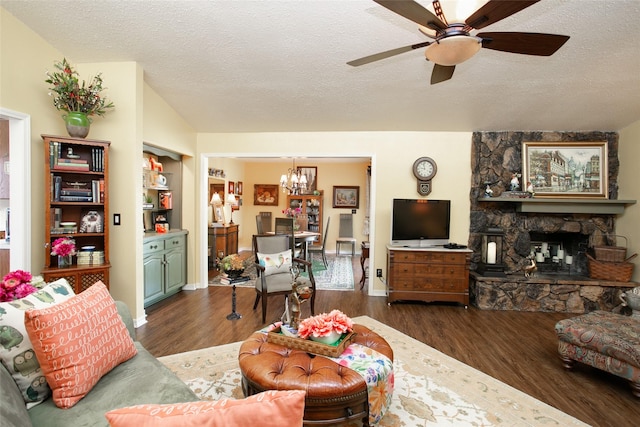 living area featuring wood finished floors, lofted ceiling, a stone fireplace, a textured ceiling, and ceiling fan with notable chandelier