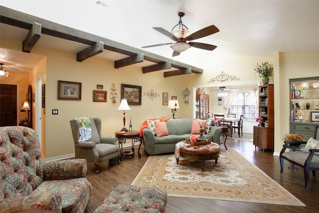 living room featuring beamed ceiling, baseboards, ceiling fan, and wood finished floors