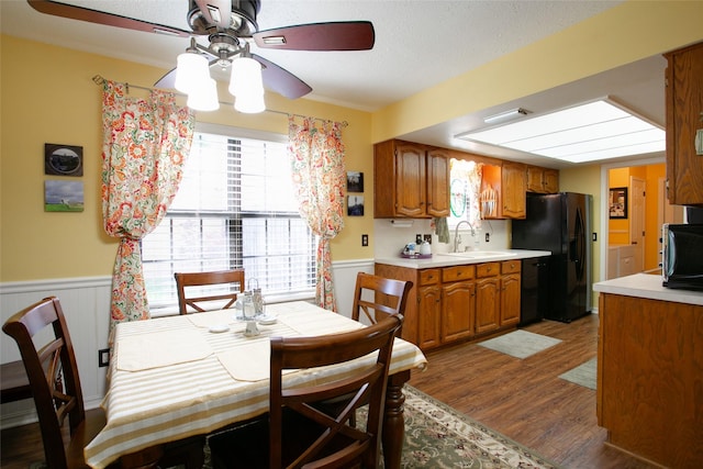 kitchen featuring a sink, a wainscoted wall, black appliances, and light countertops