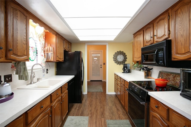 kitchen featuring brown cabinetry, black appliances, light countertops, and a sink