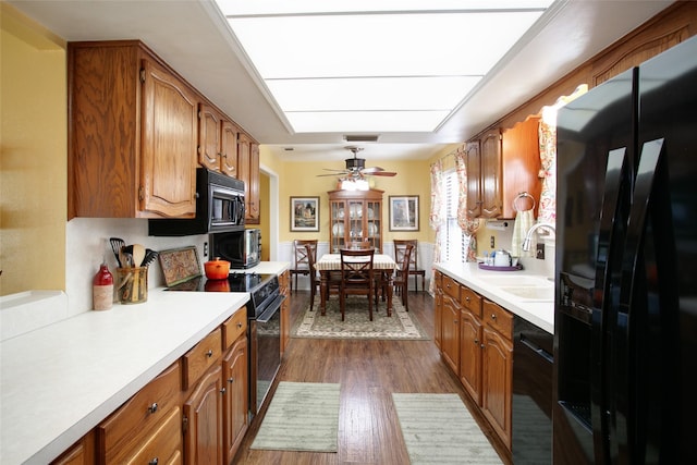 kitchen featuring a sink, black appliances, brown cabinetry, and light countertops