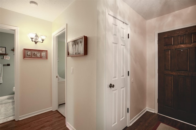 foyer with dark wood-style floors, a textured ceiling, and baseboards