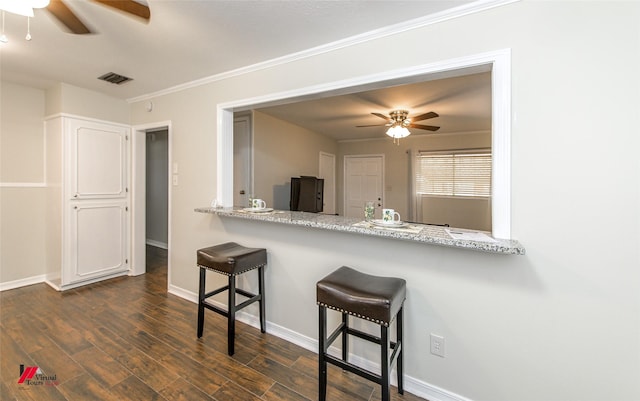 kitchen featuring a breakfast bar area, baseboards, visible vents, and dark wood-style flooring