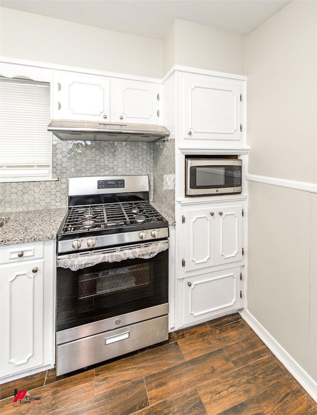 kitchen featuring dark wood-style flooring, stainless steel appliances, white cabinets, under cabinet range hood, and tasteful backsplash