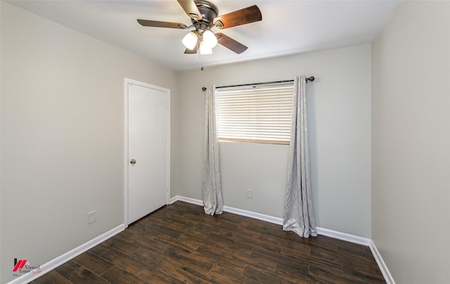 spare room featuring dark wood finished floors, a ceiling fan, and baseboards