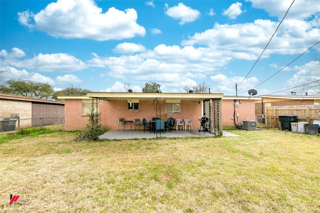 rear view of property with brick siding, fence, central AC, a lawn, and a patio area