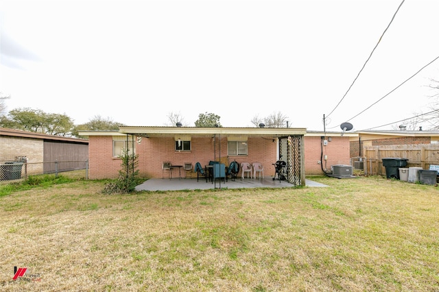 back of property with brick siding, a lawn, a patio, and fence