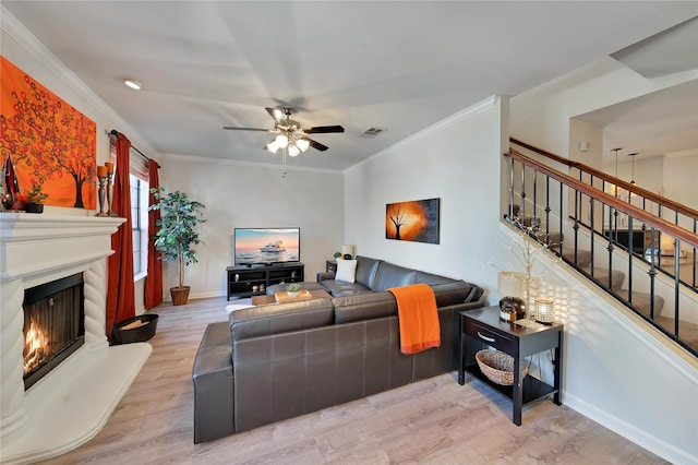 living area featuring visible vents, light wood-style flooring, stairway, and a lit fireplace