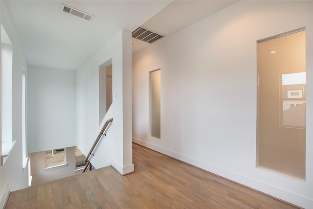 empty room with wood finished floors, visible vents, and baseboards