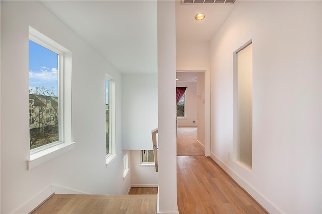 corridor featuring recessed lighting, visible vents, baseboards, and light wood finished floors