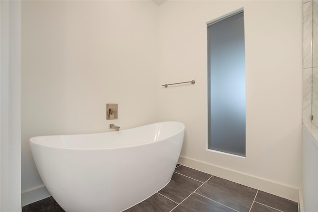 bathroom featuring tile patterned floors, baseboards, and a freestanding bath