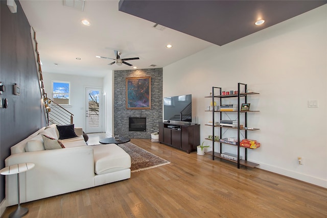 living area with a stone fireplace, stairway, wood finished floors, and visible vents