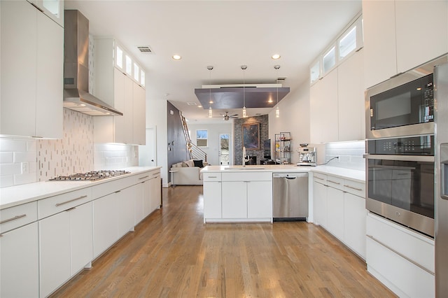 kitchen with visible vents, wall chimney range hood, open floor plan, a wealth of natural light, and stainless steel appliances