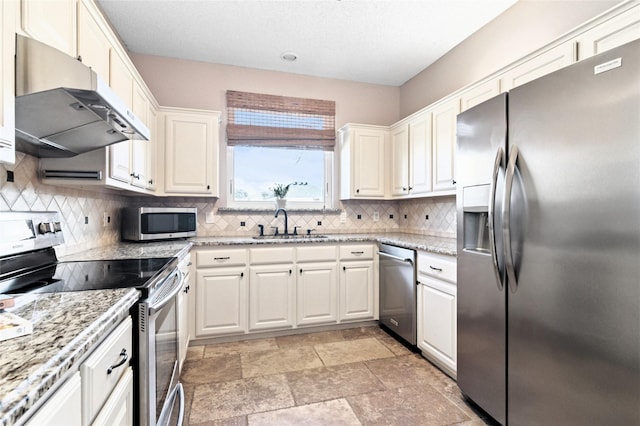 kitchen with a sink, stainless steel appliances, under cabinet range hood, white cabinetry, and backsplash