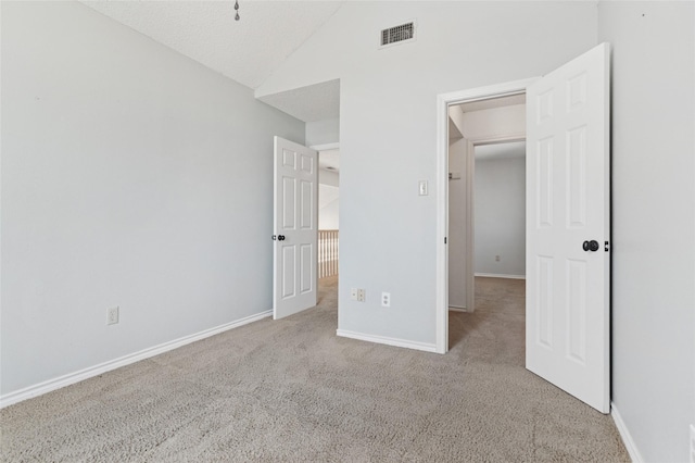 unfurnished bedroom with visible vents, carpet floors, baseboards, and vaulted ceiling