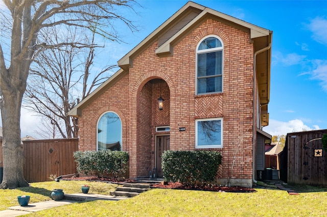 view of front of house featuring a front yard, cooling unit, fence, and brick siding