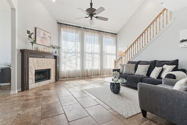 living room featuring a ceiling fan, stairs, a fireplace, and high vaulted ceiling