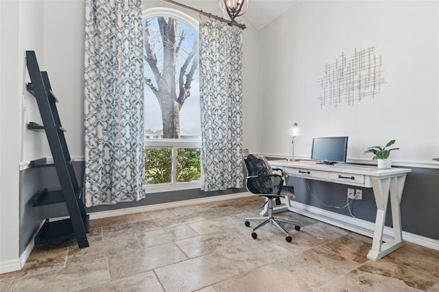 office area featuring stone finish floor, an inviting chandelier, baseboards, and vaulted ceiling