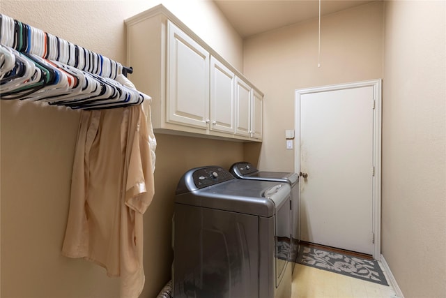 clothes washing area featuring cabinet space, independent washer and dryer, and baseboards