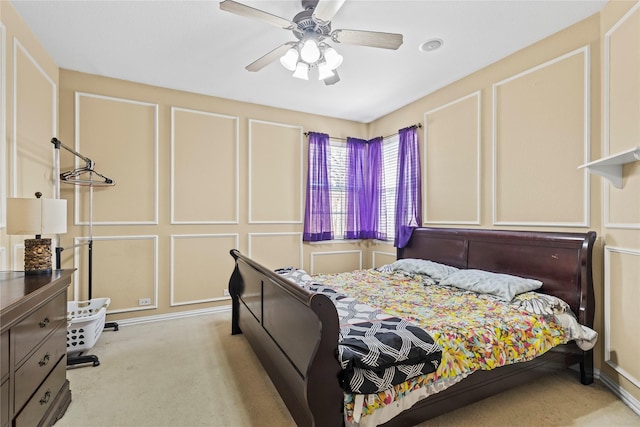 bedroom featuring light carpet, a ceiling fan, and a decorative wall