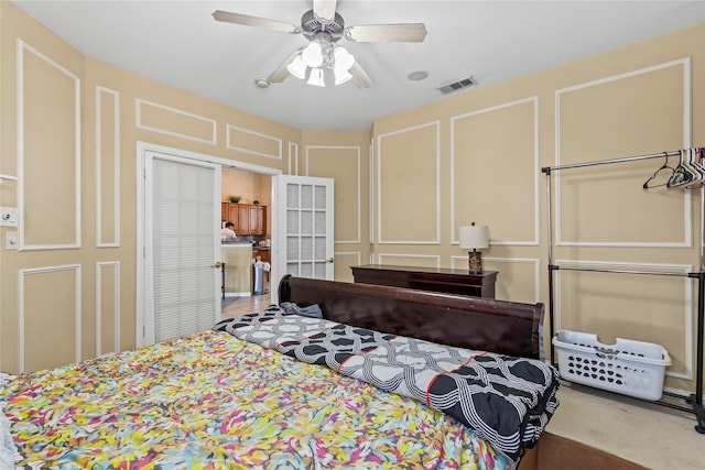 bedroom with a decorative wall, ceiling fan, and visible vents