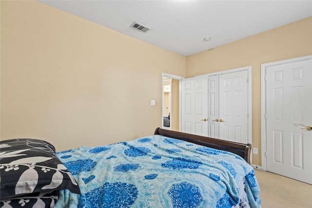 bedroom with a closet, visible vents, and light colored carpet