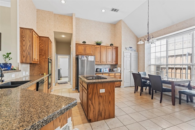 kitchen with visible vents, brown cabinets, black appliances, a sink, and a center island