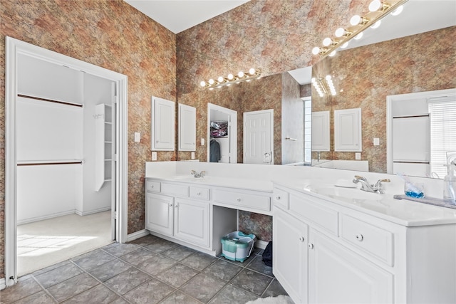 full bathroom featuring a sink, baseboards, double vanity, and a spacious closet