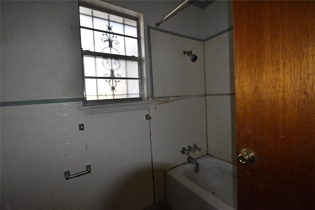 full bath with a wainscoted wall, tile walls, and  shower combination