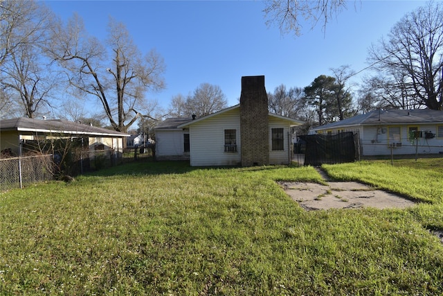 back of house featuring a lawn, a chimney, and a fenced backyard