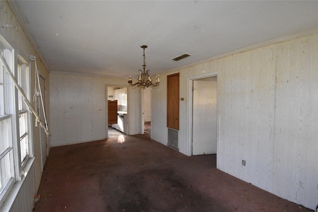 spare room featuring a notable chandelier, a healthy amount of sunlight, visible vents, and ornamental molding