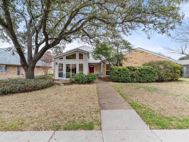 mid-century home with brick siding and a front lawn