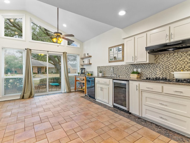 kitchen featuring a ceiling fan, stovetop, wine cooler, under cabinet range hood, and backsplash